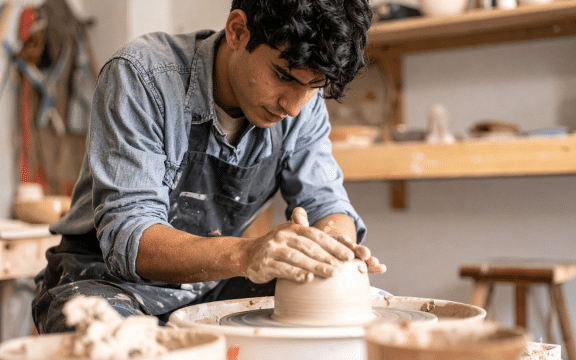 Young man practicing clay therapy on a pottery wheel during a calming session at Iyali Chennai