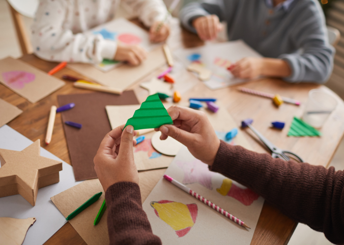 Children and adults creating handmade paper crafts and artwork during an art and craft workshop.
