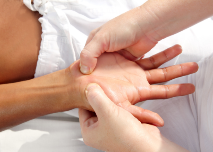 Therapist performing hand acupuncture pressure point treatment to relieve pain and improve energy balance.