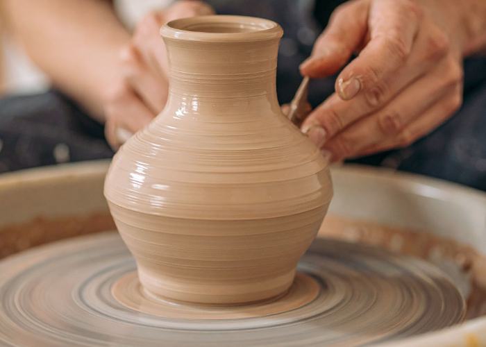 Hands shaping a clay pot on a pottery wheel during Iyali’s pottery workshop in Chennai.