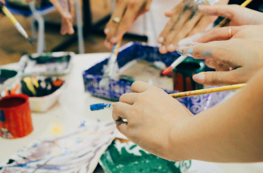 Hands of participants painting during a creative arts and crafts workshop.