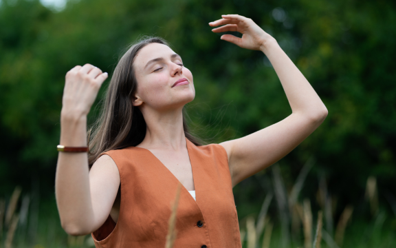 Woman practicing mindful breathing outdoors during a holistic wellness session.