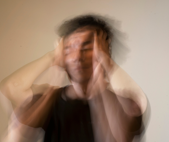 Blurred image of a stressed man holding his head, representing anxiety and emotional overwhelm.