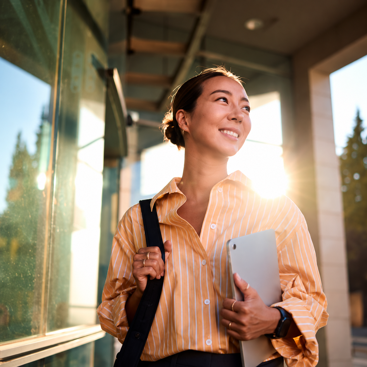 `Smiling professional woman holding a tablet outside a modern office, representing career confidence and personal growth`
