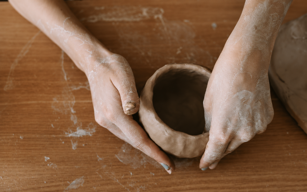 Hands shaping a handmade clay pot during a pottery class at Iyali Academy in Chennai